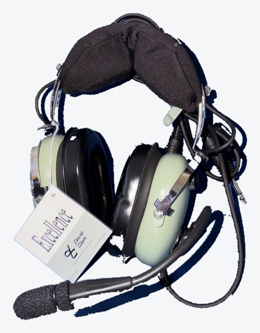 The club David Clark headset: green ear domes, black headband pad and a boom microphone, with the maker's tag still attached