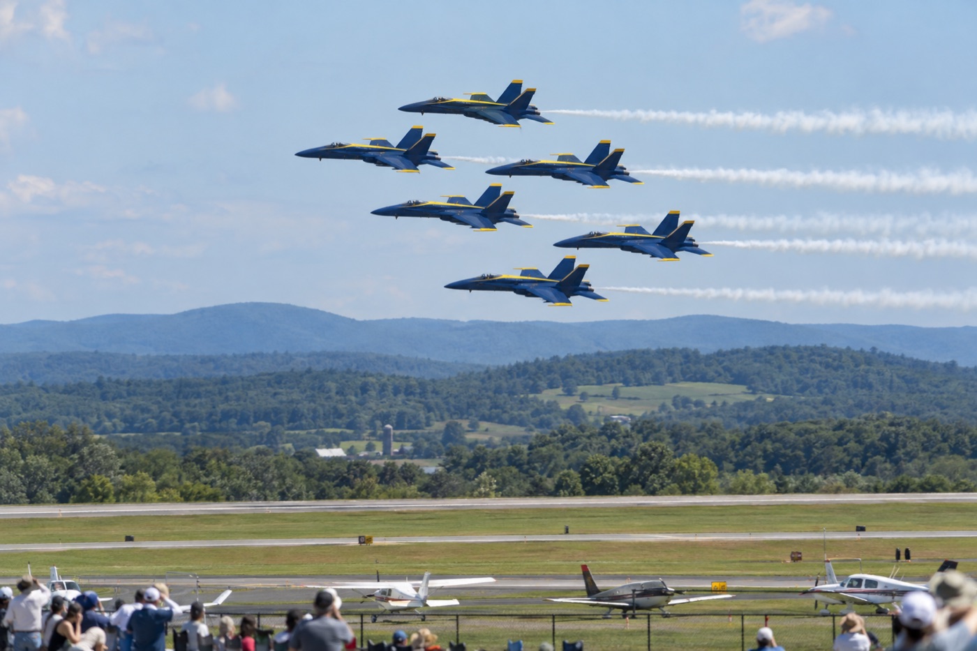 Six blue and gold demonstration jets flying in formation over the Hudson Valley